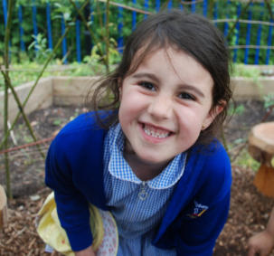 girl in school uniforms smile at camera as part of school growing project in Manchester